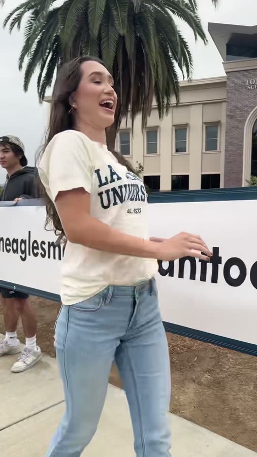 A student walking the length of a very long banner across campus.